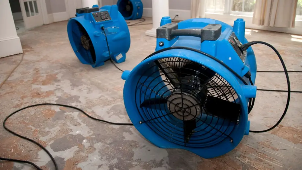 Blue air mover drying a floor after flooding