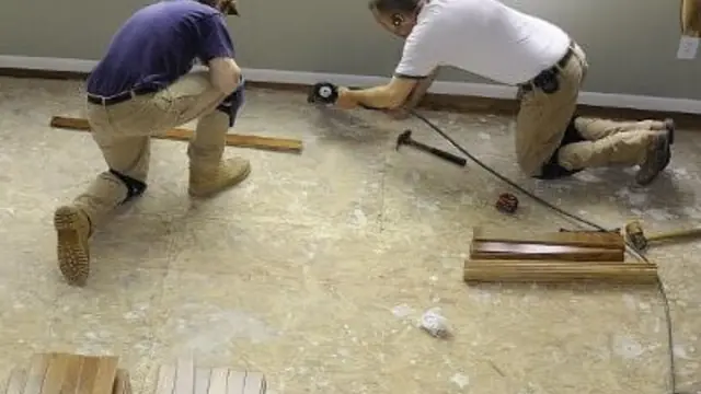 Two workers repairing a floor after water damage